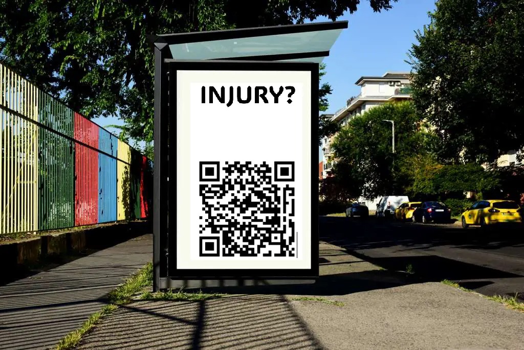 Transit shelter poster with INJURY? headline and QR code on a city sidewalk